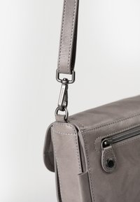 Borsa in pelle grigia con chiusura superiore a zip, caratterizzata da cuciture bianche, una tracolla removibile e una clip metallica per il fissaggio.
