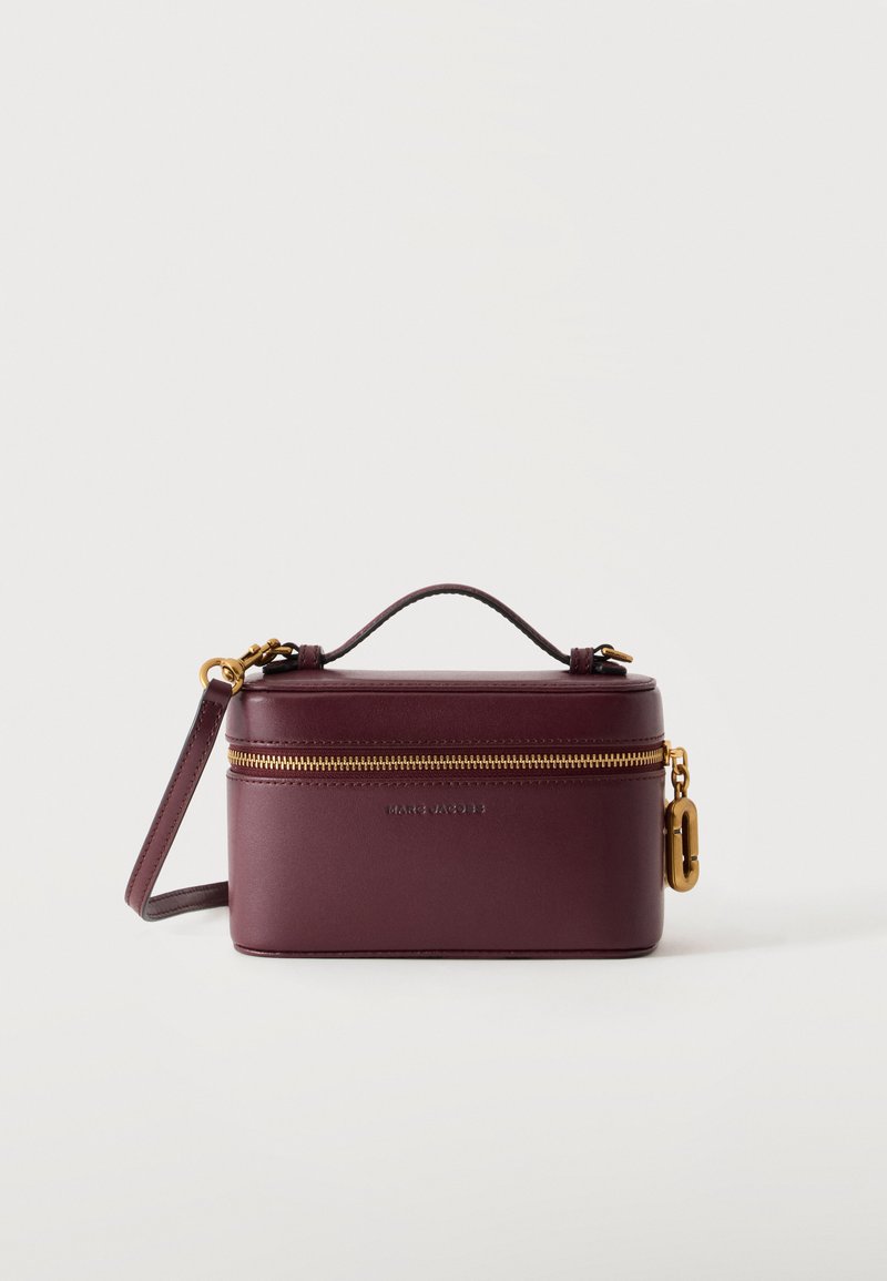 Sac à main rectangulaire en cuir bordeaux foncé avec fermeture éclair dorée, poignée courte sur le dessus, bandoulière amovible et charm logo doré sur le côté.