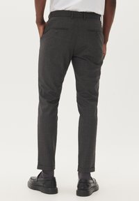 Pantalones ajustados de cuadros grises con bolsillos laterales, bolsillos traseros con botones y dobladillos enrollados. Hechos de una tela suave, ideales para ocasiones formales.