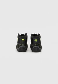 Black high-top sneakers with mesh panels, lime green accents, and a textured rubber sole. Features a logo on the heel and stitched detailing.