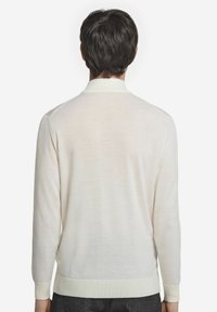 Vitt långärmad tröja med ribbat krage och manschetter, med en slät textur och minimalistisk design. Bakåtsidan visar inga logotyper eller mönster.