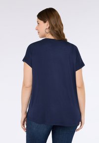 Navy blue lyhythihainen paita, jossa on rento malli, pyöreä kaula-aukko ja sileä pinta. Sisältää sivurei'än ja suoran helman.