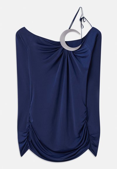 Temno modra bluzka z drapiranim dizajnom in off-shoulder izrezom, ki ima krožni kovinski detajl in nagubane detajle ob straneh. Gladka tekstura.
