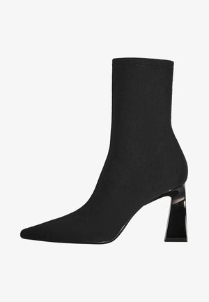Bottine noire en maille avec bout pointu et talon bloc brillant, design lisse et élégant s'étendant au-dessus de la cheville.