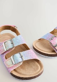 Glitzernde rosa und blaue Sandale mit zwei verstellbaren Riemen und metallischen Schnallen. Korkfußbett und strukturierte Laufsohle für besseren Halt.