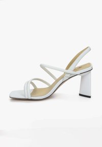 Witte sandaal met banden en een vierkante neus, voorzien van een blokhak en gemaakt van glad kunstleer. Minimalistische stijl met neutrale accenten.
