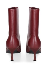 Bottines en cuir bordeaux avec un bout rond, un haut talon aiguille et une finition lisse et élégante. Présente un design minimaliste.