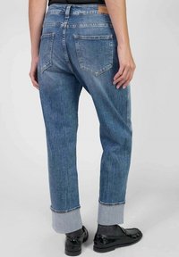 Jeans de mezclilla de alta cintura en azul claro, con un corte relajado, puños doblados y dos bolsillos traseros que presentan un patrón de costura distintivo.