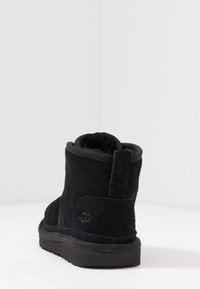 Stivale alla caviglia in suede nero con punta arrotondata, superficie testurizzata e suola in gomma resistente. Caratterizzato da un piccolo tappo posteriore e logo in rilievo.