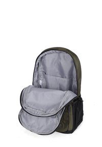 Sac à dos vert olive avec un intérieur en nylon gris, ouverture zippée et rabat frontal. Comprend une petite poche en mesh sur le côté.