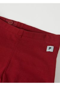 Punaiset puuvillahousut, joissa on sileä pinta, nappi vyötäröllä ja pieni etiketti, jossa lukee "POLARN" ja logo sivulla.