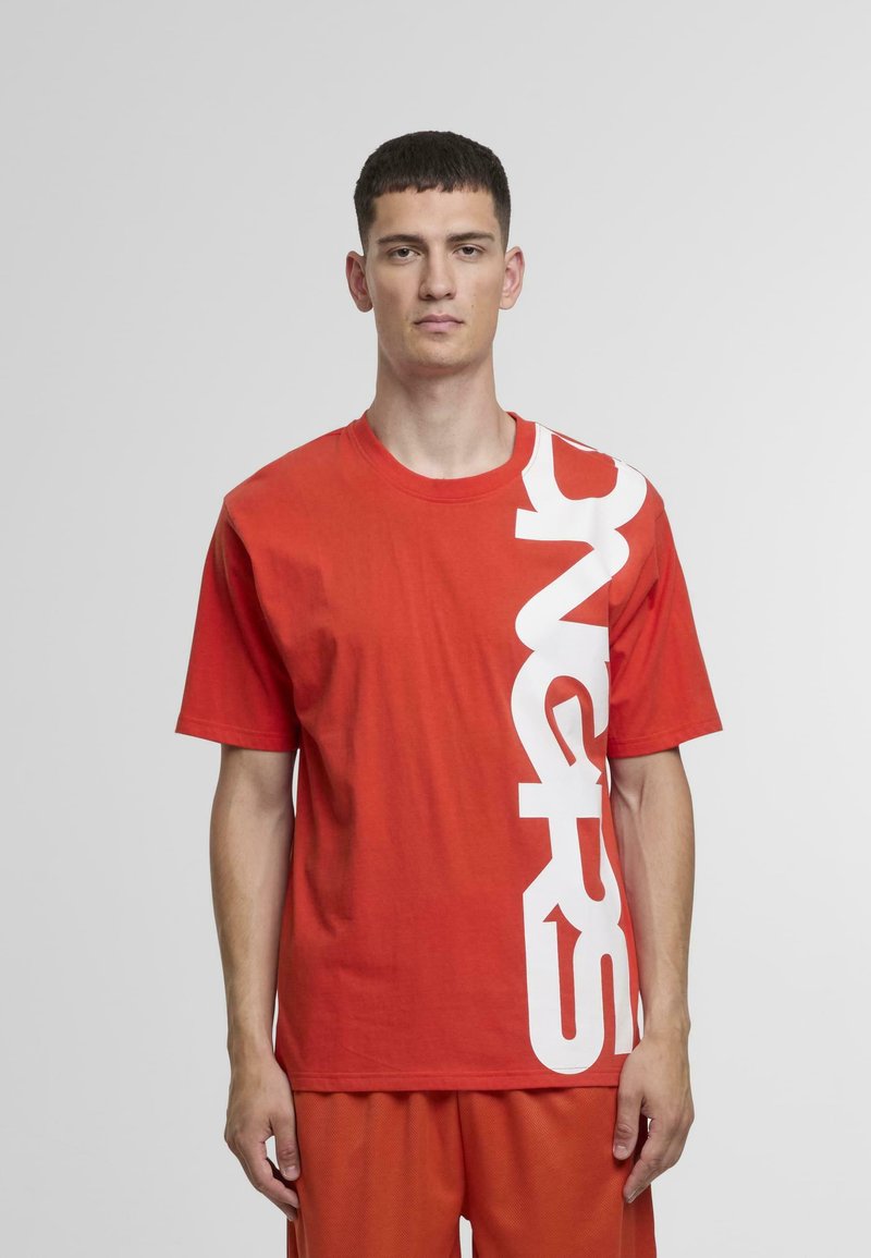 Κόκκινο βαμβακερό T-shirt με μεγάλο λευκό γραφικό σχέδιο κατά μήκος της αριστερής πλευράς, χαλαρή εφαρμογή και στρογγυλή λαιμόκοψη, συνδυασμένο με αντίστοιχα σορτς.