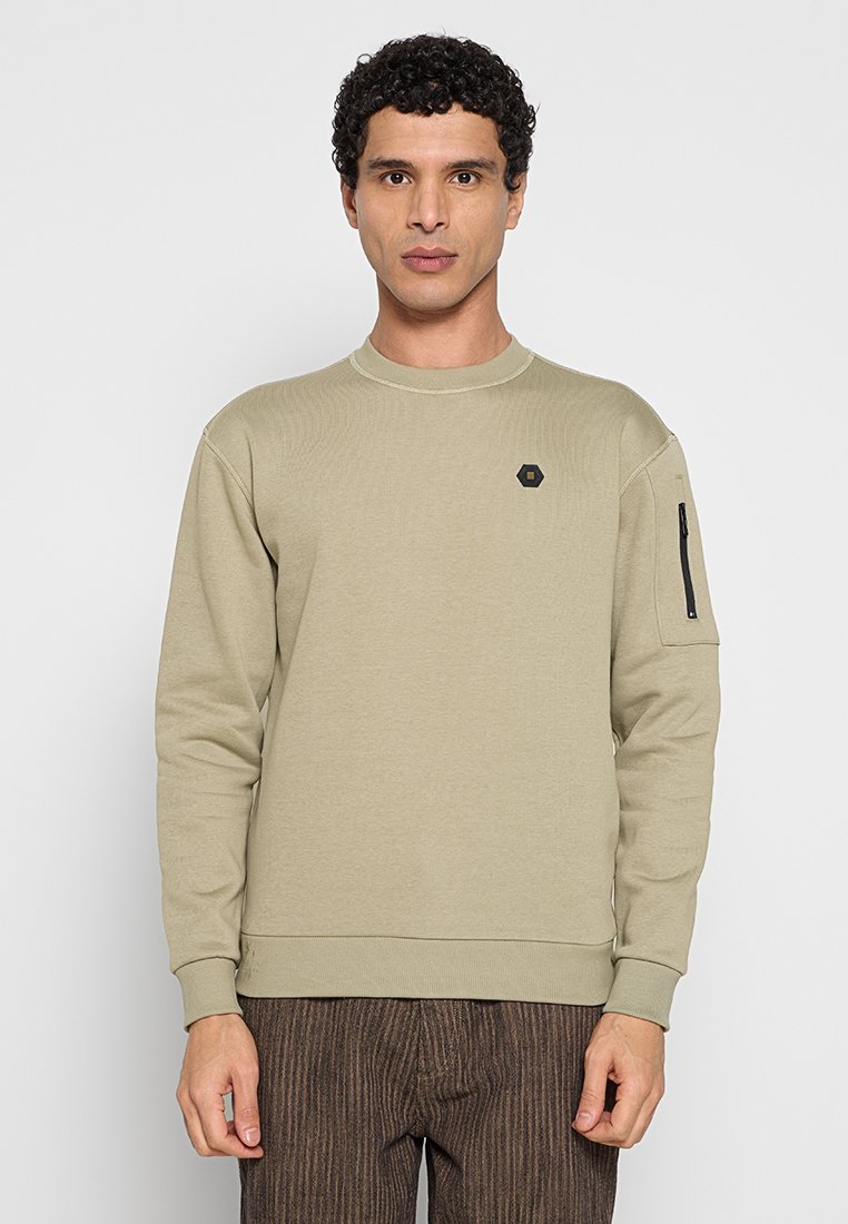 Khaki sweatshirt met een ronde halslijn, geribbelde textuur en een ritssluiting op de linkermouw. Zwart zeshoekig logo op de borst.