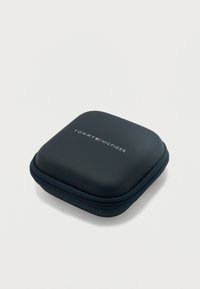 Συμπαγής μαύρη τετράγωνη θήκη με φερμουάρ, με το λογότυπο Tommy Hilfiger και έμβλημα σημαίας σε κόκκινο, λευκό και μπλε στην κορυφή.