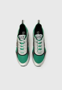 Zöld és ezüst sportcipők hálós felsőrésszel, szürke részletekkel, jól látható márkajelzéssel és fűzős kialakítással, saroknál húzófüllel.