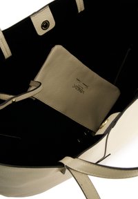Beige læder tote taske med sort indvendig, med en guld trykknap og en aftagelig beige pung indeni. Glat struktur, minimalistisk design.