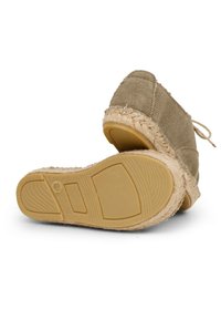Beige espadrilles with a textured upper, natural jute trim, and a rubber sole featuring a zigzag pattern and logo detail.