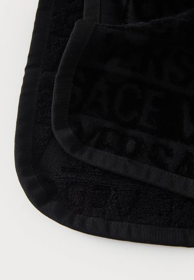 Fekete törölköző, texturált felülettel, finom mintázattal és fekete szegéllyel. A szövet lágynak és bolyhosnak tűnik, ideális a szárításhoz.