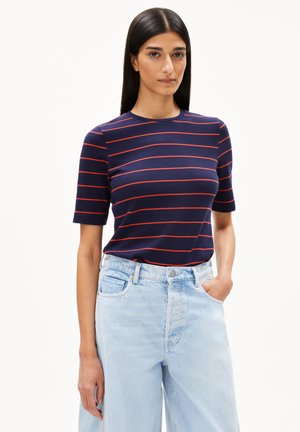 Marineblaues T-Shirt mit roten horizontalen Streifen, Rundhalsausschnitt, kurzen Ärmeln, kombiniert mit hochgeschnittenen hellblauen Jeans.