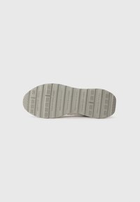 Shoe sole in light gray rubber, featuring textured patterns and branding. The design includes horizontal and vertical grooves for traction.