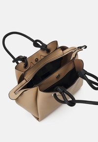 Beżowa skórzana torebka z czarnymi akcentami, posiadająca dwie przegrody, kieszeń na zamek błyskawiczny oraz podwójne uchwyty w formie sznura. Gładka faktura ze srebrnymi elementami.