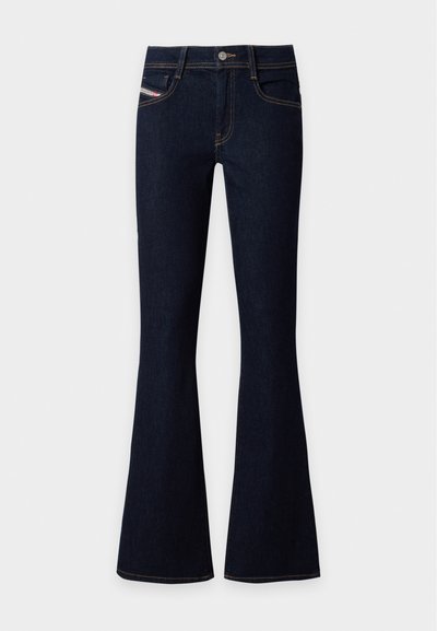 Jean en denim bleu foncé taille haute avec jambe évasée, fermeture devant par bouton et zip, et détails de couture visibles.