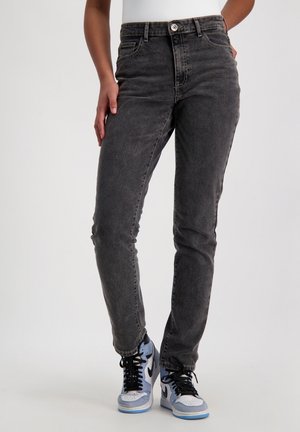 Verbleekte zwarte denimjeans hebben een hoge taille, slim fit, standaard vijf-pocket ontwerp en een knoopsluiting. Draagt met lichtblauwe sneakers.