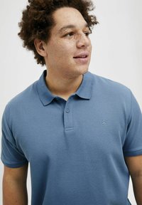Korte mouw polo-shirt in lichtblauw, met een gestructureerde stof, voorzien van een knoopsluiting kraag en een klein logo op de linkerborst.