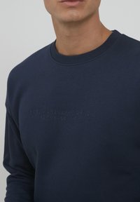 Sweatshirt blu navy realizzato in morbido tessuto, con scollatura a costine e testo in rilievo che riporta "BLEND ORIGINAL DENIM EST. 93 - DANIMARCA."