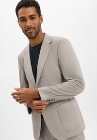 Lichtgrijze blazer gemaakt van textuurstof, met een enkele borstzak, twee frontzakken en accenten van vier knopen op de mouwen.