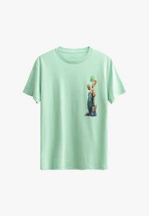 T-shirt en coton vert menthe avec un graphique coloré de deux personnages en salopette, l'un tenant un ballon vert, sur le côté avant gauche.
