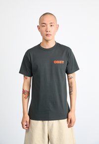Dark gray cotton t-shirt with "OBEY" printed in orange on the chest, short sleeves, and a classic crew neckline. Smooth texture.