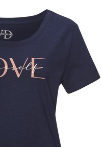 Námornícky modré bavlnené tričko s okrúhlym výstrihom a krátkymi rukávmi. Predný textový dizajn v ružovo-zlatej farbe znie "MILUJ seba," s kurzívou.