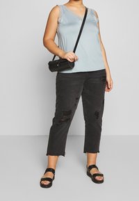 Ljusblå ärmlös topp med spetsdetaljer, ihop med svarta slitna cropped jeans och svarta sandaler. Liten svart crossbody-väska.