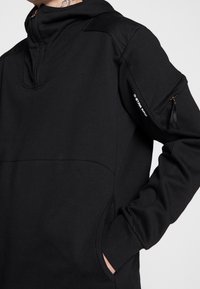 Černá mikina s kapucí se zipovým límcem, boční kapsou a logem G-Star Raw na rukávu. Vyrobena z hladkého, elastického materiálu.