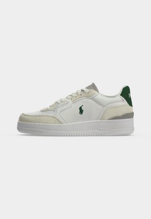 Weißer Sneaker mit niedrigem Schaft, beigen Wildleder-Akzenten, grünem Logo an der Seite und am Fersenlasche, weißer Sohle und Schnürverschluss.