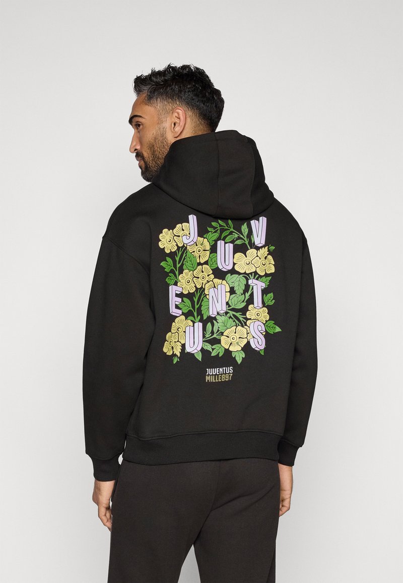 Mustaga kapuutsiga dressipluus, millel on värvikas lilleline graafika ja sõna "Juventus" seljal helesinistes ja kollastes toonides.