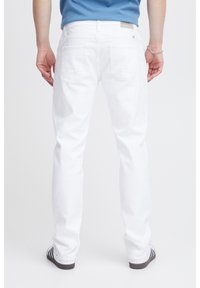 Jeans de mezclilla blanca con un corte recto, dos bolsillos traseros y una etiqueta de marca en la cinturilla. La textura parece suave y casual.