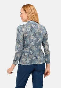 Patronen lange mouwen top in blauw met bloemenontwerpen. Zachte stof met een lichte glans, slimfit silhouet en een ronde halslijn.