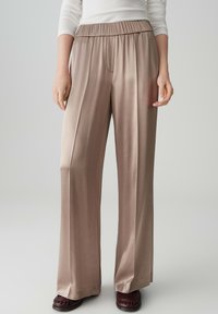 Beige wijde broek met een gladde, glanzende textuur en een elastische tailleband. Heeft een recht model en is gemaakt van lichtgewicht stof.