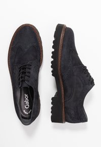 Marineblaue Wildleder-Oxford-Schuhe mit Wingtips, einer braunen genähten Sohle und einer robusten schwarzen Gummisohle. Mit Schnürdesign.