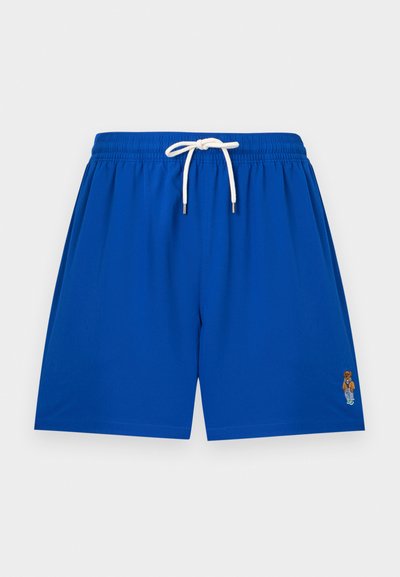 Niebieskie spodenki kąpielowe z białym sznurkiem i małym haftowanym logo misia na dolnej prawej nogawce, przedstawione na jednolitym tle.