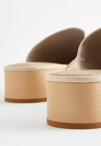 Bēša platforma zābaki ar teksturētu gaiši bēšu bloku papēdi un gludu augšējo materiālu. Ielocīta forma un mīksta zolīte.