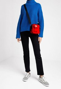 Chunky blue knit turtleneck sweater, black straight-leg pants, red crossbody bag, and gray sneakers. Textured fabric and contrasting colors.