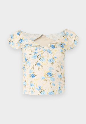 Krótkie, kość słoniowa bluzka z odkrytymi ramionami, bufkami i niebieskim kwiatowym nadrukiem, z małym przednim węzłem.