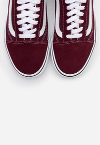 Paire de baskets en daim bordeaux avec lacets blancs et bande latérale blanche, vues de dessus sur fond blanc.