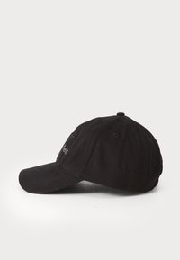 Zwarte baseballcap met een gebogen rand, gemaakt van katoen, met een gestructureerd oppervlak en een geborduurd logotipdetail aan de zijkant.