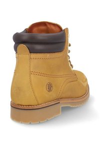 Botín de tobillo marrón y beige con parte superior de cuero texturizado, detalles de costura, cuello acolchado y suela de goma; logo grabado en el lateral.