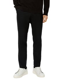 Zwarte broek van lichtgewicht stof, slim fit, met een gladde textuur en zijzakken. Gecombineerd met witte sneakers.