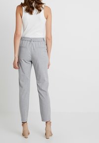 Světlé šedé kalhoty s jemným proužkem a přiléhavým střihem, s předními kapsami, hladkým textilním povrchem a zúženým střihom nohavic.